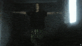 a person with their arms outstretched in a dark room with a window in the background