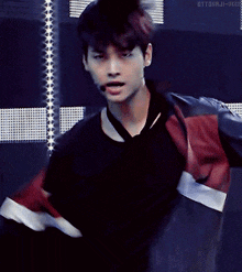 a man with a microphone in his mouth is wearing a black shirt and red jacket