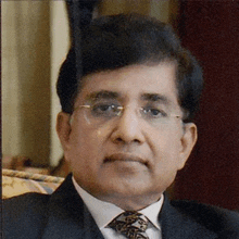 a man wearing glasses and a suit is sitting on a chair