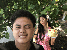 a man making a funny face while a woman holds a small cake
