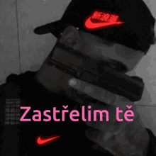 a man wearing a nike hat holds a gun in his mouth