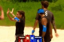 a man and a woman giving each other a high five in front of a scoreboard that says 6