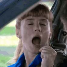 a woman yawning while sitting in a car