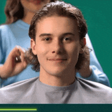 a man is getting his hair cut by a woman in a blue shirt