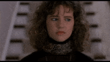 a woman with curly hair is wearing a black turtleneck