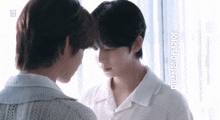 two men are touching each other 's foreheads in front of a sign that says km1 on it