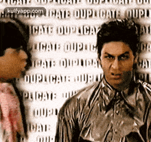 a man in a striped shirt is standing next to another man in a striped shirt and looking at the camera .
