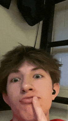 a young man is making a funny face with his finger on his mouth