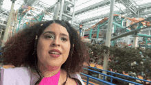 a woman is standing in front of a roller coaster in an amusement park .