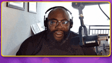 a man wearing glasses and headphones is standing in front of a shure microphone
