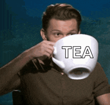 a man is drinking from a large cup that says tea