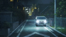 a car is driving down a street at night with the headlights on