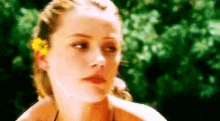 a woman with a flower in her hair looks at the camera .