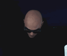 a bald man wearing sunglasses stands in a doorway