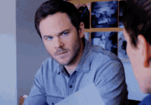 a man in a blue shirt looks at another man