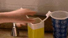a person brushing their teeth next to a blue cup with flowers