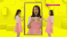 a woman in a pink dress is standing in front of a mirror .