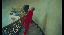 a woman in a red suit is walking down stairs