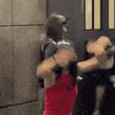 a woman in a red tank top is dancing in front of a man in a black hat .