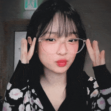 a girl wearing glasses and a black and white sweater has a sign above her head that says ' exit ' on it