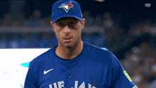 a baseball player wearing a blue jays jersey looks at the camera