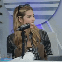 a woman in a leather jacket is sitting in front of a microphone .