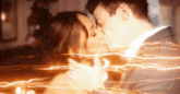 a man and a woman are kissing in front of a light trail