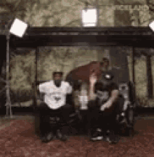 a group of people are sitting in chairs in front of a wall with trees on it .