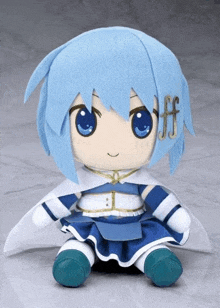 a stuffed doll with blue hair and blue eyes is sitting on a white surface