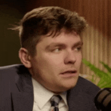 a close up of a man in a suit and tie talking into a microphone .