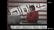 a woman in a red jacket is typing on a keyboard in front of a computer monitor .