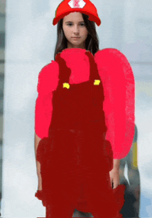 a girl is wearing overalls and a red hat with a k on it