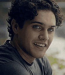 a close up of a man 's face with curly hair smiling .
