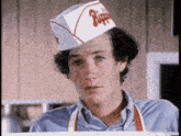 a man wearing a chef 's hat and apron is standing in a restaurant .