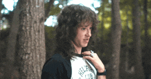 a man with curly hair wearing a shirt that says hellfire club