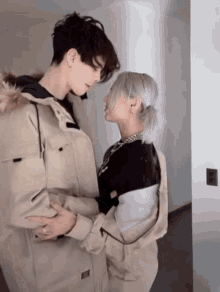 a man and a woman are looking at each other and the woman is wearing a necklace