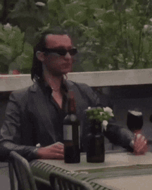 a man sitting at a table with a bottle of wine in his hand