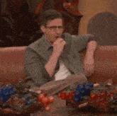 a man sits on a couch with a bowl of gummy bears on the table