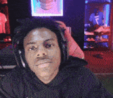 a man wearing headphones and a black shirt with the number 7 on it laughs