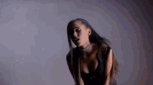 ariana grande is wearing a choker and a plunging neckline in a black dress .
