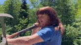 a woman in a blue shirt is holding a pair of scissors over her shoulder .