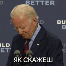 a man in a suit and tie stands in front of two microphones with the word better written on the back