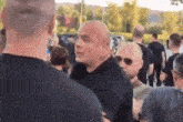a group of men are standing in a line talking to each other in a crowd .