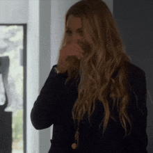 a woman with long blonde hair is covering her face with her hand