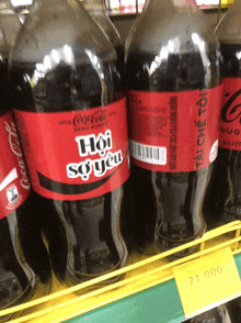 two bottles of coca cola are on a shelf