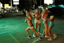 a group of young women are dancing on the side of the road