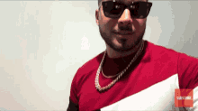 a man wearing sunglasses and a red shirt has the word subscribe on the bottom right