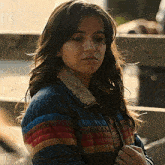 a woman wearing a striped jacket looks at the camera