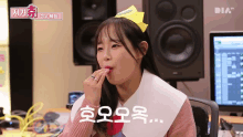 a girl with a yellow sticky note on her head is eating something