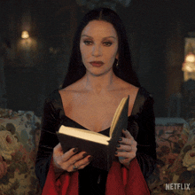 a woman in a black dress is holding a book with a netflix logo in the background